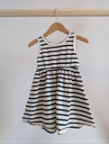 Pale yellow sleeveless baby romper with button closure on the legs, hanging on a wooden hanger.